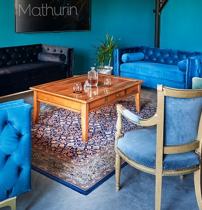 Espaces privatisables : salon bleu et noir avec table basse en bois et tapis persan.