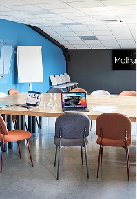 Espaces privatisables : salle de réunion moderne avec tables, chaises et tableau blanc.