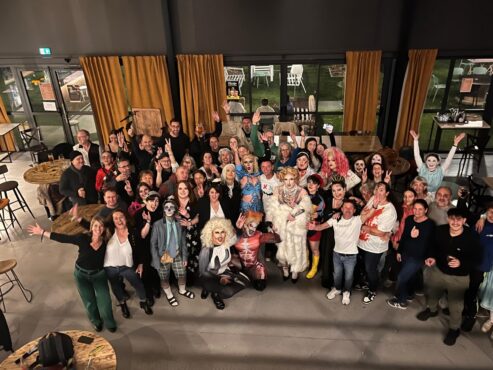 Soirée à thème : groupe costumé, drag queens et musiciens lors d'un événement festif.