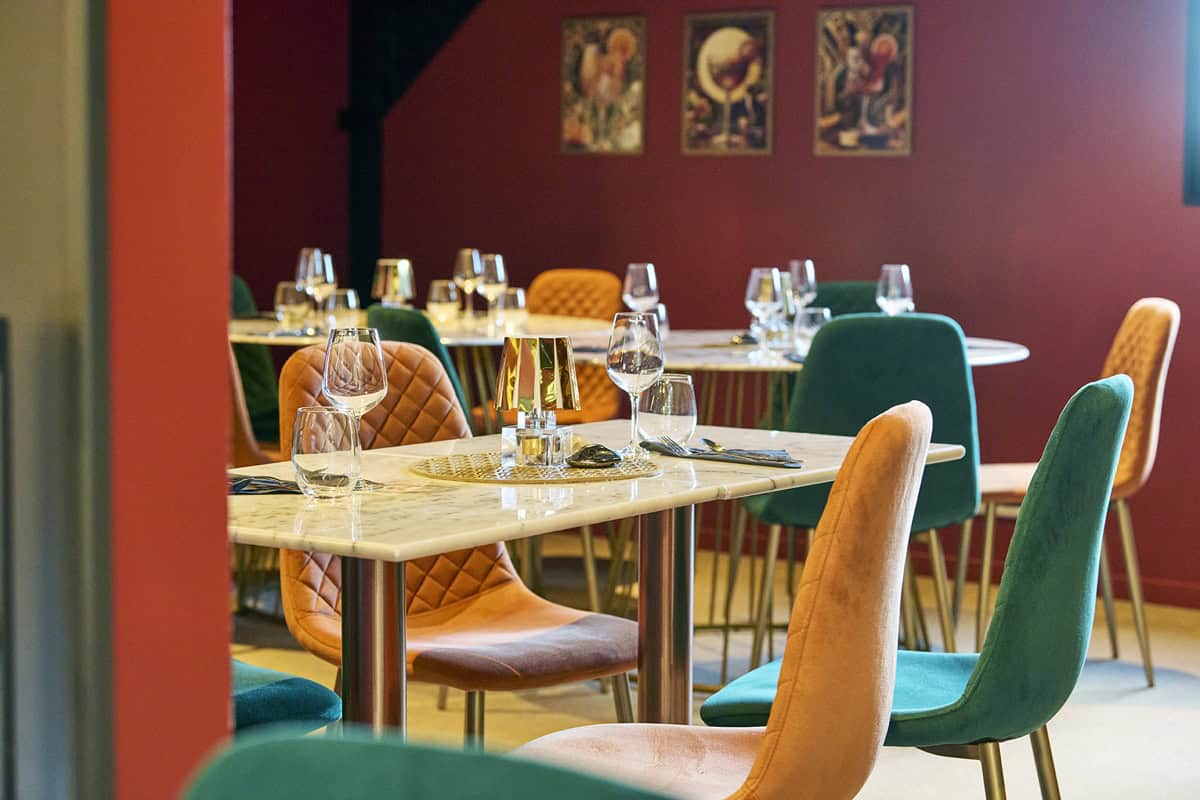 Tables dressées dans un restaurant bistronomique avec des chaises colorées.